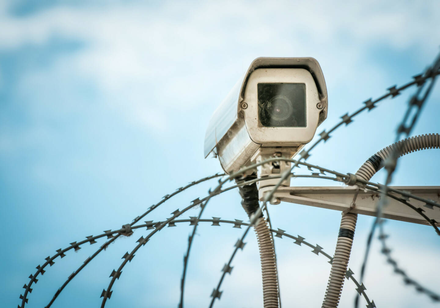 Überwachung, Kamera, Stacheldraht, sicher, gesichert, versperrt, Spionage, Sicherheit, eingesperrt, http://www.shutterstock.com/de/pic-132392237/stock-photo-close-up-view-of-security-camera-hanging-among-barbwire-in-prison-or-other-guarded-object-with-blue.html 