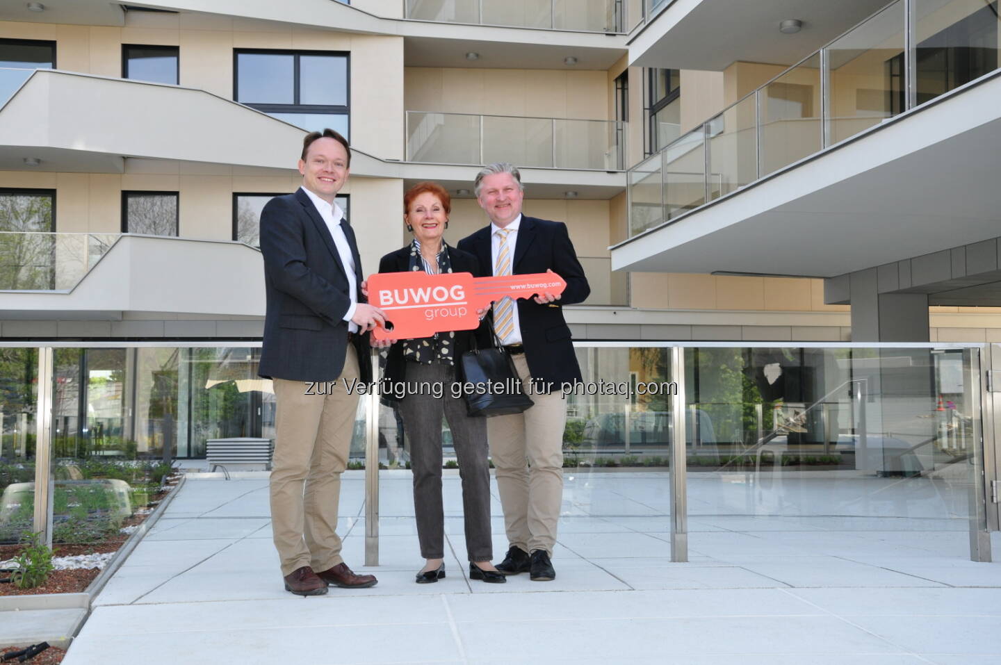 Alexander Steppan, Development Manager bei der BUWOG Group, und Peter Friedrich Berchtold, Leiter der Vertriebsabteilung bei der BUWOG Group in Österreich, übergeben symbolisch den Schlüssel an eine neue Bewohnerin der Pfarrwiesengasse 23. (Fotocredit: Buwog Group)